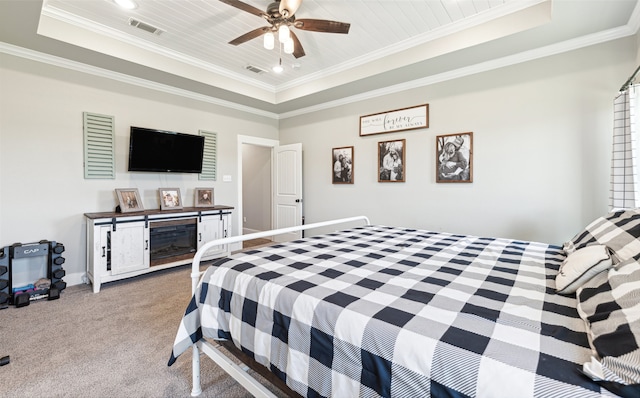 carpeted bedroom featuring a tray ceiling, crown molding, and ceiling fan