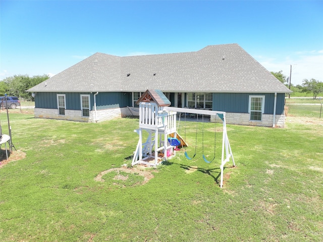 back of house with a playground and a lawn