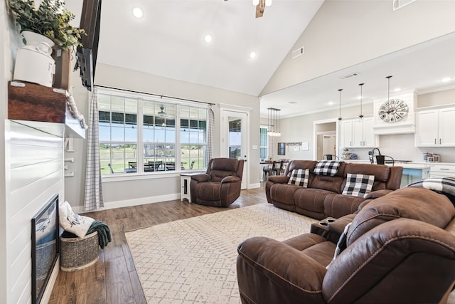 living room with crown molding, light hardwood / wood-style flooring, ceiling fan, and high vaulted ceiling