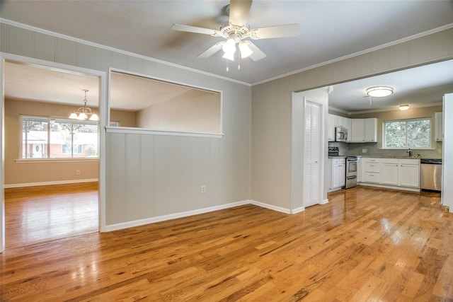 interior space featuring backsplash, white cabinets, light hardwood / wood-style flooring, ornamental molding, and stainless steel appliances