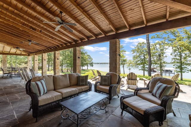 view of patio with ceiling fan, an outdoor living space, and a water view