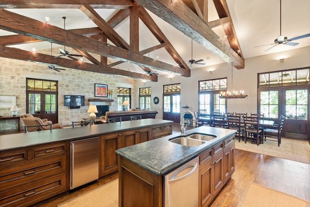 kitchen with sink, french doors, an island with sink, ceiling fan with notable chandelier, and stainless steel dishwasher