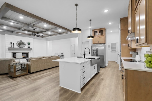 kitchen featuring white cabinetry, stainless steel refrigerator with ice dispenser, a center island with sink, and light wood-type flooring