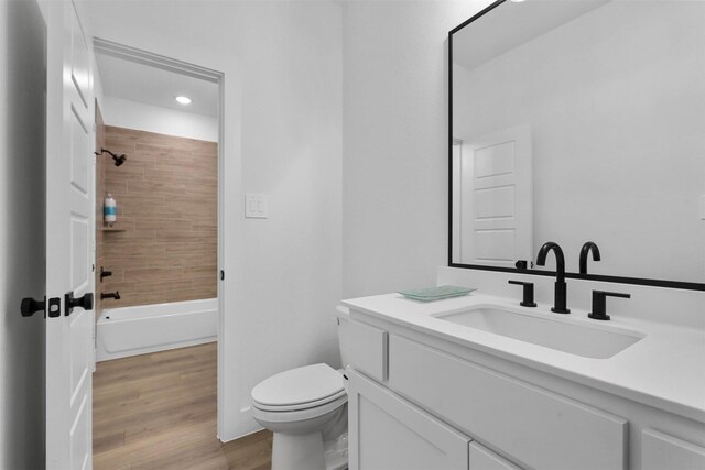 full bathroom with hardwood / wood-style floors, vanity, toilet, and tiled shower / bath