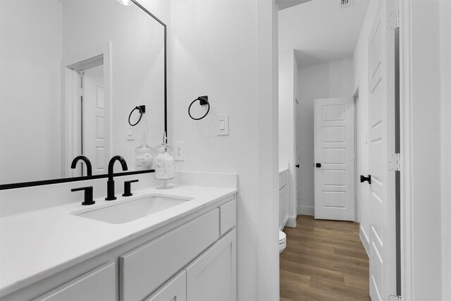 bathroom with toilet, vanity, and wood-type flooring