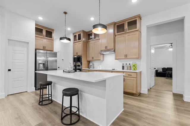 kitchen featuring light hardwood / wood-style floors, hanging light fixtures, an island with sink, ceiling fan, and appliances with stainless steel finishes