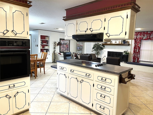 kitchen featuring black appliances, a brick fireplace, light tile patterned floors, kitchen peninsula, and a textured ceiling