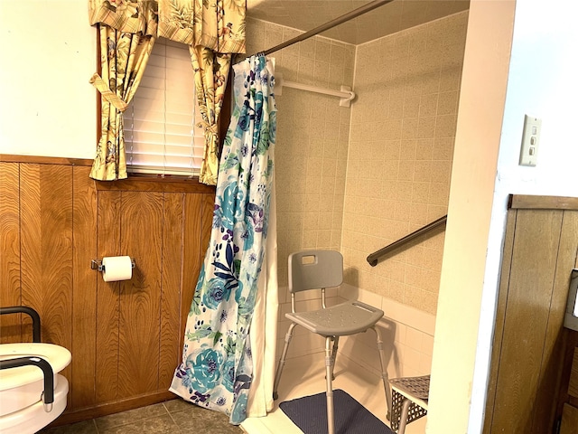 bathroom with wooden walls, toilet, and tile patterned floors