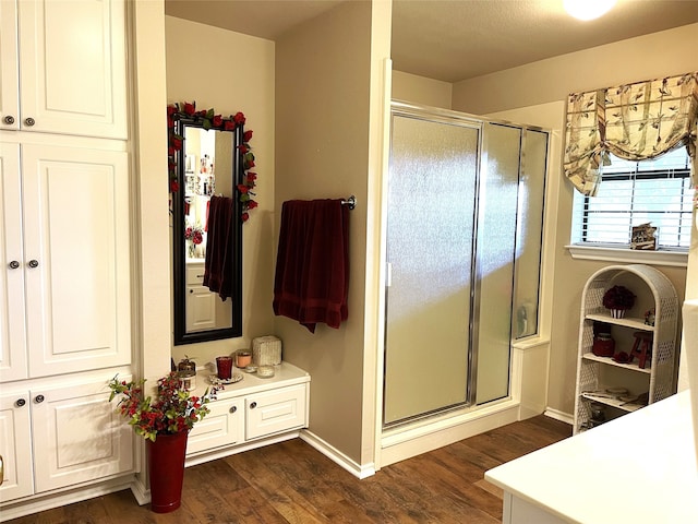 bathroom with a shower with shower door and hardwood / wood-style flooring