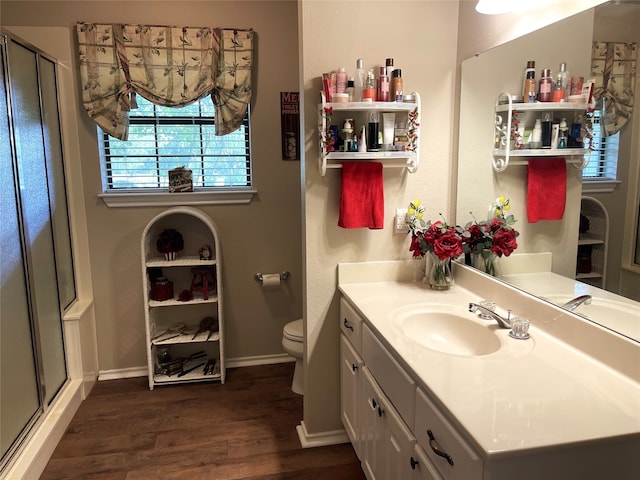 bathroom featuring toilet, hardwood / wood-style flooring, walk in shower, and vanity