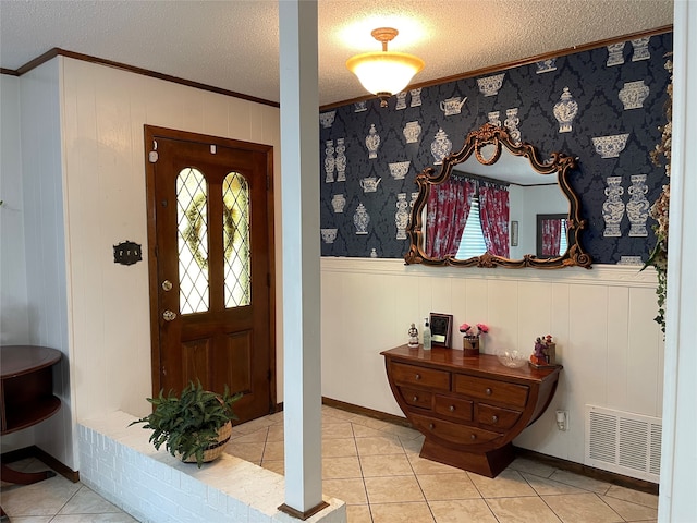 foyer entrance featuring a textured ceiling, ornamental molding, and light tile patterned floors