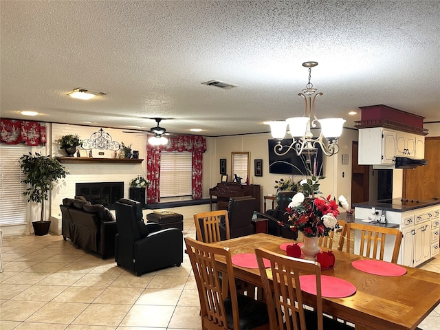 tiled dining room with ceiling fan with notable chandelier and a textured ceiling