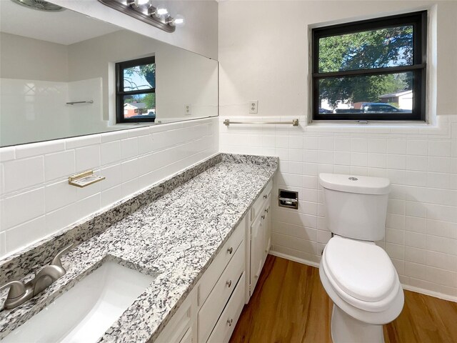 bathroom featuring tile walls, toilet, hardwood / wood-style floors, and vanity