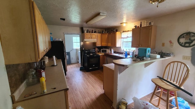 kitchen with light hardwood / wood-style flooring, sink, a textured ceiling, black electric range oven, and kitchen peninsula