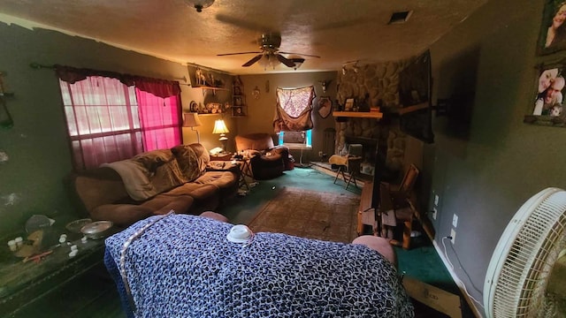 carpeted living room featuring a textured ceiling, ceiling fan, and a stone fireplace