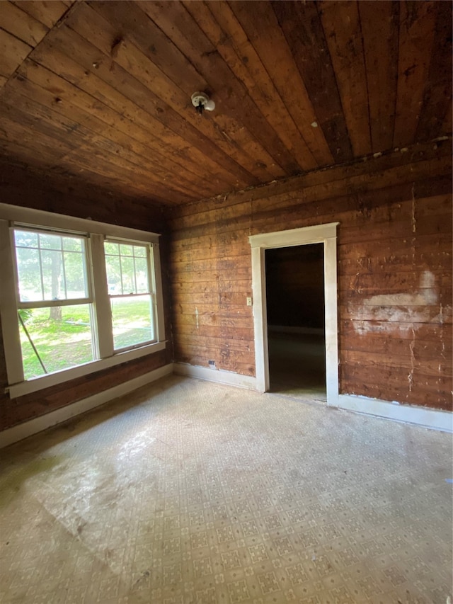 unfurnished room featuring wooden walls and wooden ceiling