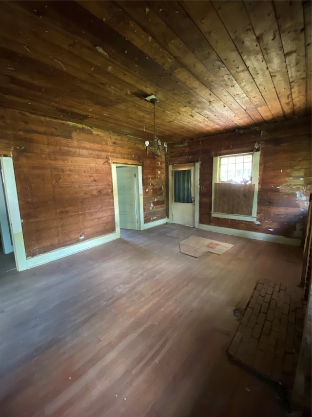 unfurnished living room with wood ceiling, wooden walls, a chandelier, and wood-type flooring