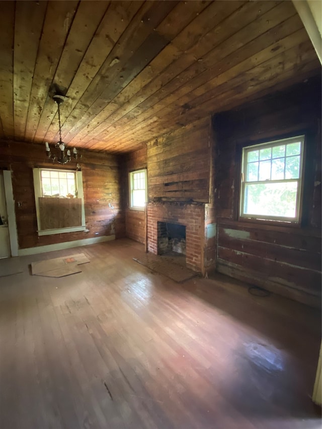 unfurnished living room with a chandelier, wood ceiling, wood walls, hardwood / wood-style flooring, and a fireplace