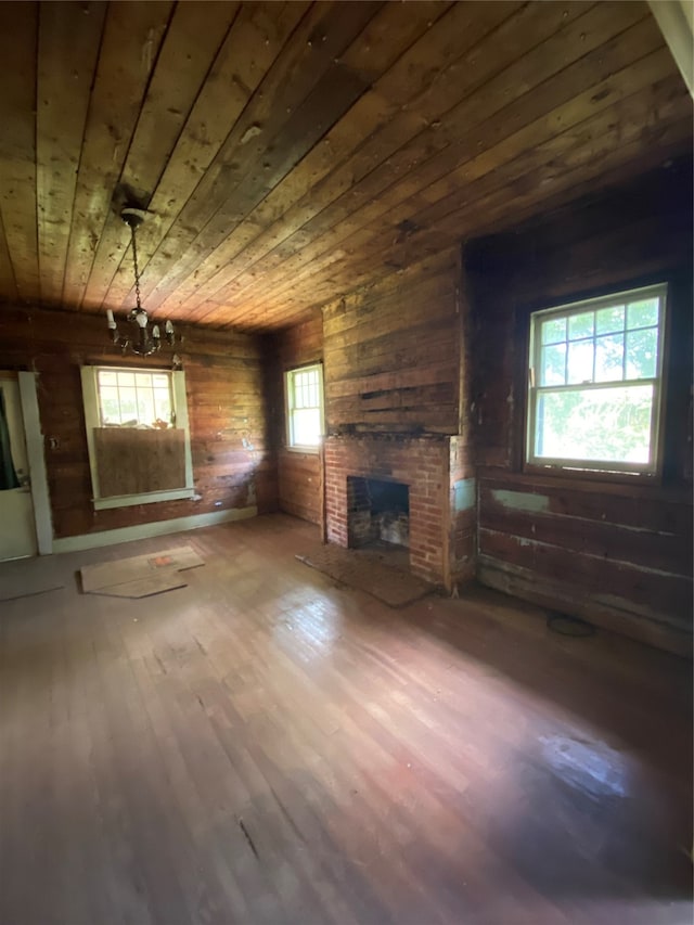 unfurnished living room with a fireplace, wooden walls, wooden ceiling, and hardwood / wood-style floors