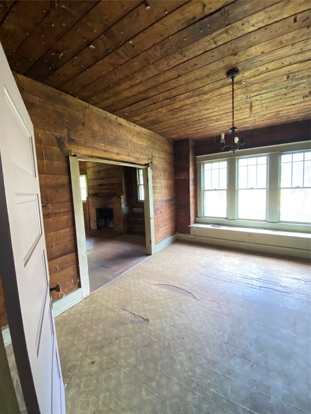 unfurnished living room featuring wood walls, an inviting chandelier, and wooden ceiling