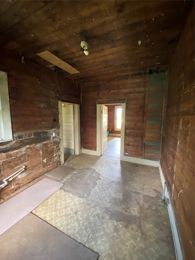 spare room featuring wood walls and concrete floors