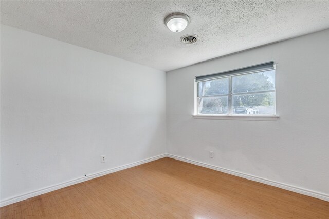 unfurnished room featuring hardwood / wood-style floors and a textured ceiling