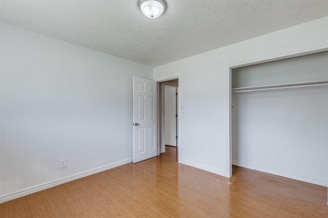 unfurnished bedroom with a closet, a textured ceiling, and light hardwood / wood-style floors