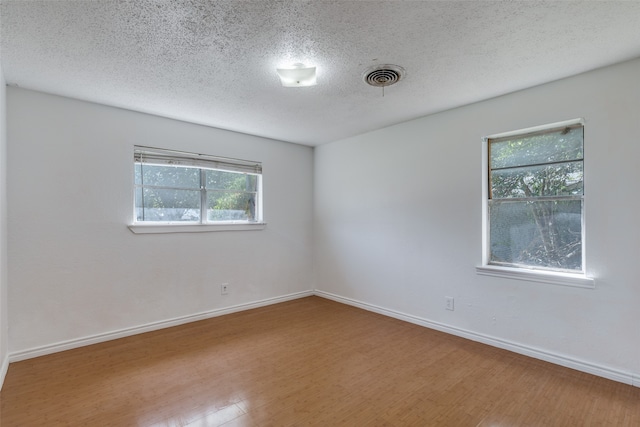 empty room with wood-type flooring and a textured ceiling