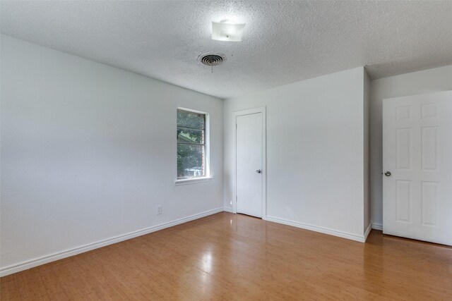 unfurnished room featuring a textured ceiling and hardwood / wood-style floors