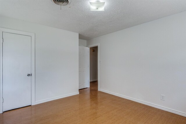 unfurnished room with wood-type flooring and a textured ceiling