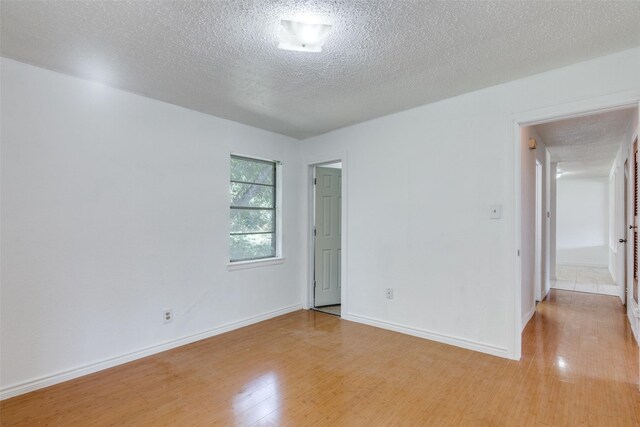 spare room featuring a textured ceiling and light hardwood / wood-style floors