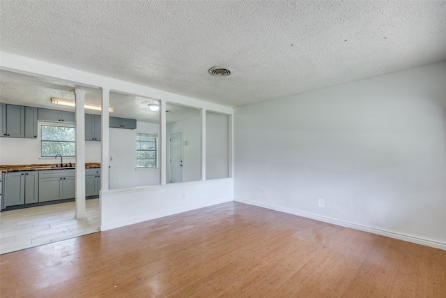 spare room featuring sink, light hardwood / wood-style flooring, and a textured ceiling