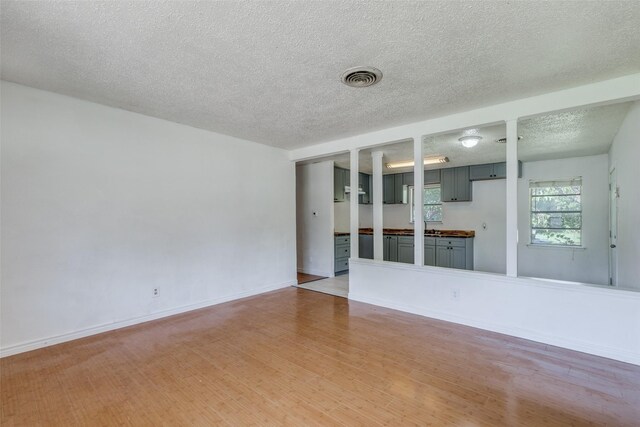 spare room with light wood-type flooring and a textured ceiling