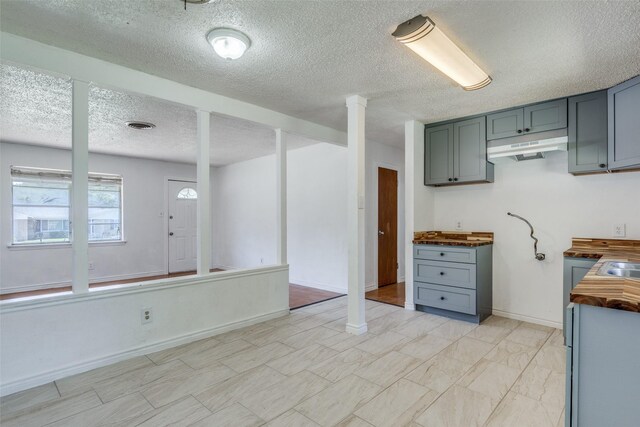 kitchen with light tile patterned flooring, wooden counters, decorative columns, and a textured ceiling