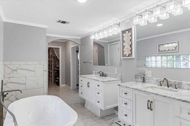 bathroom with a tub to relax in, crown molding, tile patterned floors, dual bowl vanity, and tile walls