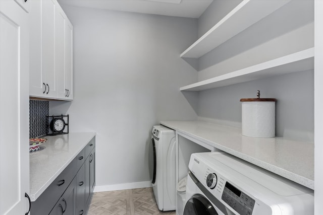 laundry area featuring light parquet flooring, washing machine and dryer, and cabinets