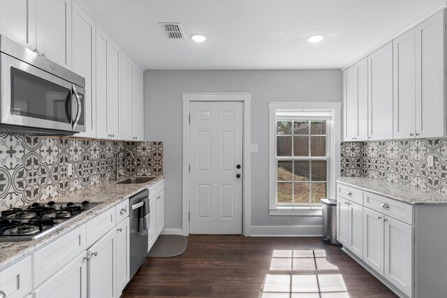 kitchen with backsplash, dark hardwood / wood-style floors, white cabinetry, appliances with stainless steel finishes, and sink