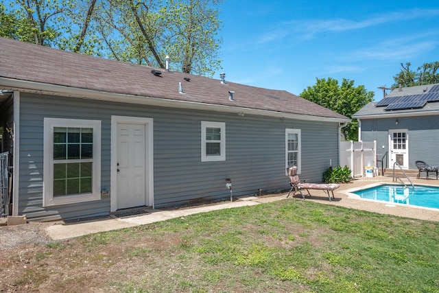 rear view of property with a lawn and solar panels