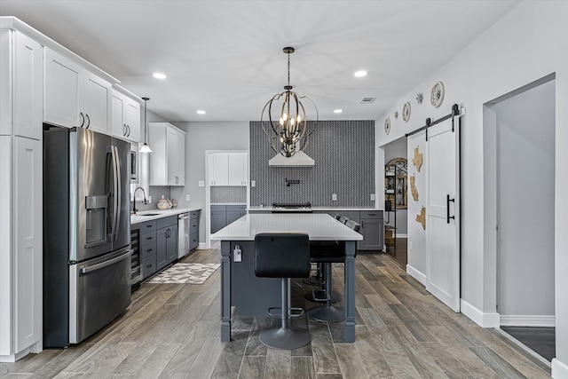 kitchen featuring backsplash, stainless steel refrigerator with ice dispenser, dark hardwood / wood-style floors, and a barn door