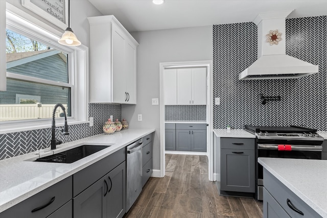 kitchen with tasteful backsplash, custom exhaust hood, sink, decorative light fixtures, and range with gas stovetop