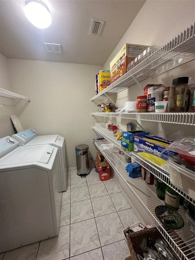 laundry area featuring washing machine and clothes dryer, a textured ceiling, and light tile patterned flooring