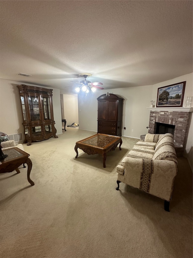 sitting room featuring a textured ceiling, carpet flooring, ceiling fan, and a brick fireplace