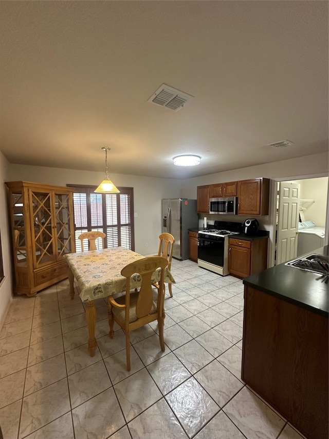 kitchen featuring stainless steel appliances, decorative light fixtures, and light tile patterned floors