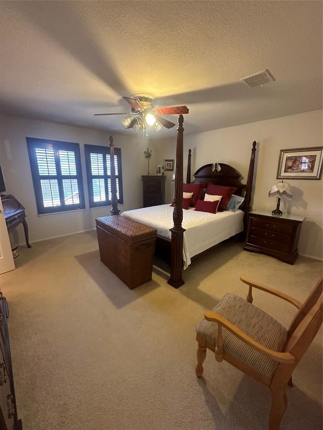 bedroom with ceiling fan, a textured ceiling, and light carpet