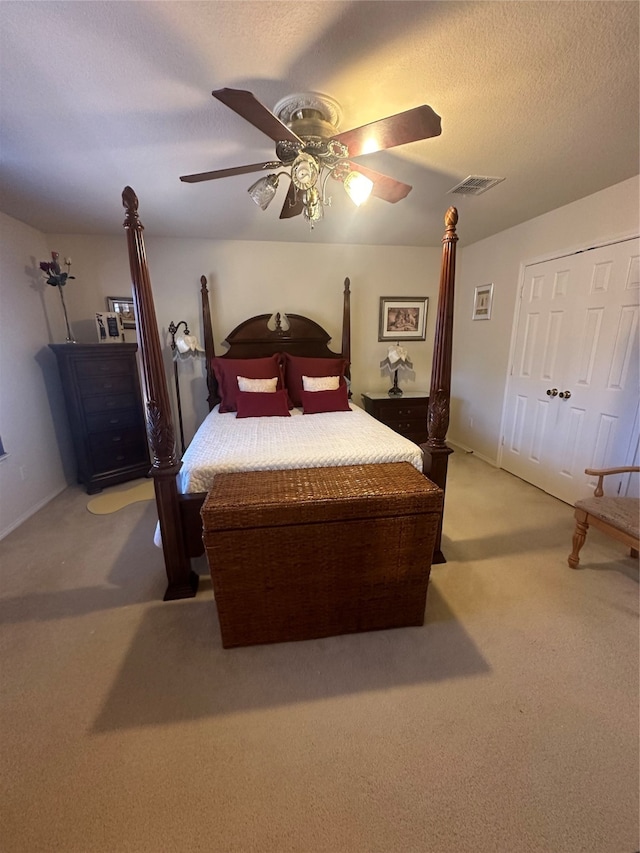 bedroom with a textured ceiling, a closet, ceiling fan, and light carpet