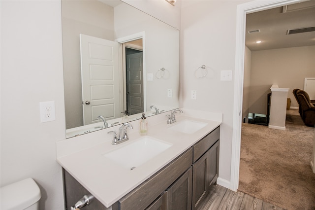 bathroom with hardwood / wood-style flooring, toilet, and double vanity