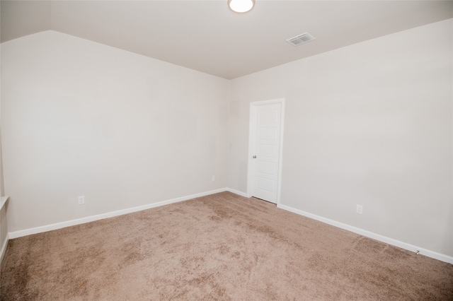 carpeted empty room with vaulted ceiling