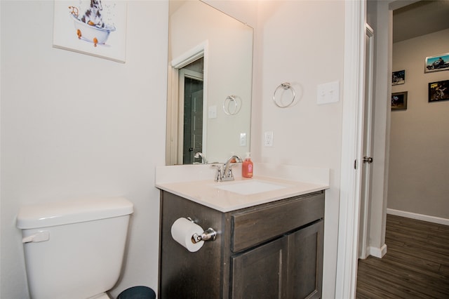 bathroom with hardwood / wood-style flooring, toilet, and vanity