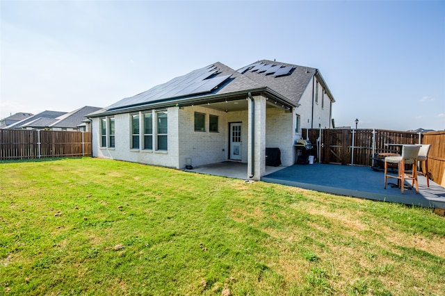 rear view of property with solar panels, a patio area, and a yard