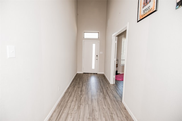 entryway with light hardwood / wood-style floors and a towering ceiling